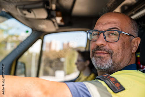 Quadro su tela Paramedic driving ambulance with colleague in the background