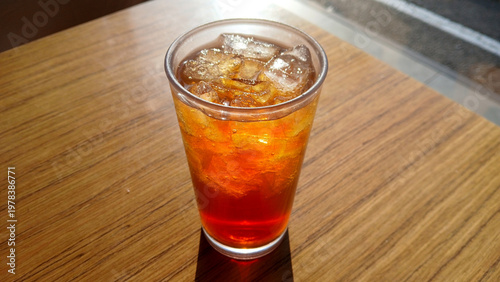 close up of iced tea or cold brew coffee with ice cubes in a glass on a table with warm sunlight and lens flare at an outdoor cafe
