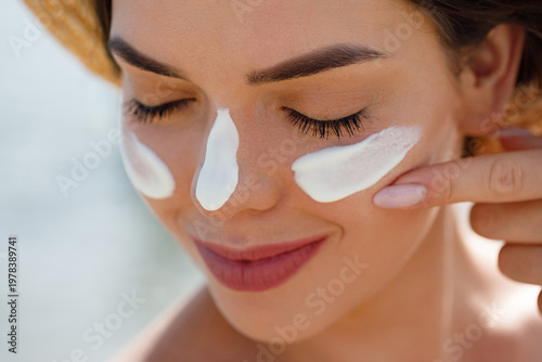 Beauty, suntan spf and skincare cosmetics model face portrait, woman with moisturizing cream. Girl using sunscreen to skin. Sunscreen product or sun tan lotion on her cheek