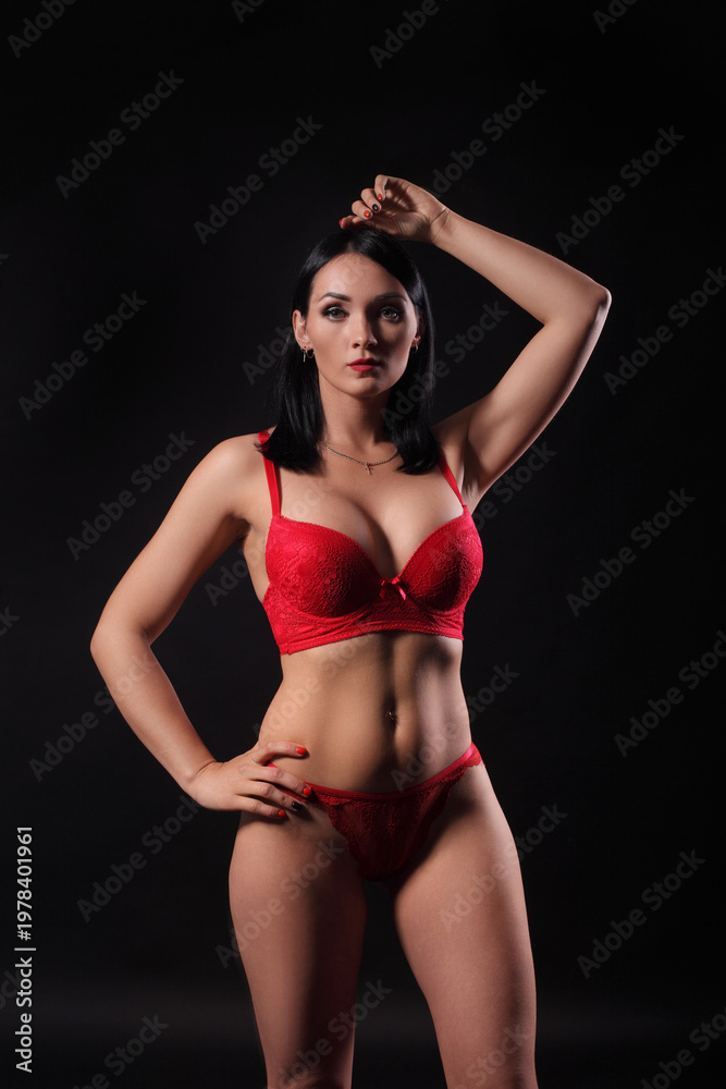 Fototapeta premium Sexy woman posing in red lingerie on dark background