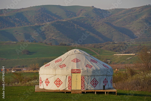 Kazakh national yurt on a green field against a background of hills. Traditions, the Nauryz spring festival. Country life.