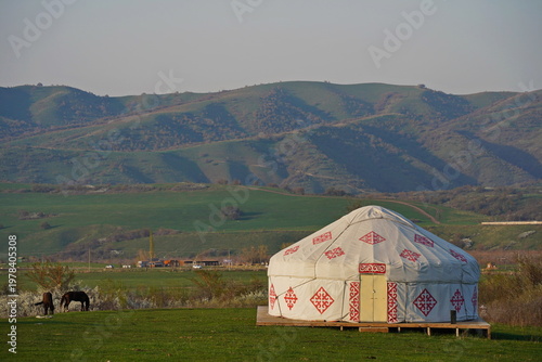 Kazakh national yurt on a green field against a background of hills. Traditions, the Nauryz spring festival. Country life.