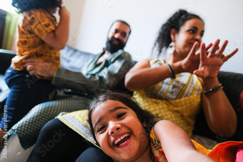 Canvas Print Happy female indian kid taking selfie with mobile phone camera at home with brot