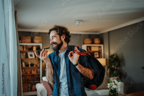 Tableau sur toile Happy man talking on speakerphone preparing for travel