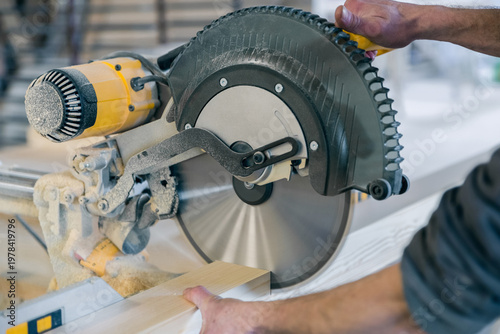Tableau sur toile Worker cuts a wooden beam circular saw.
