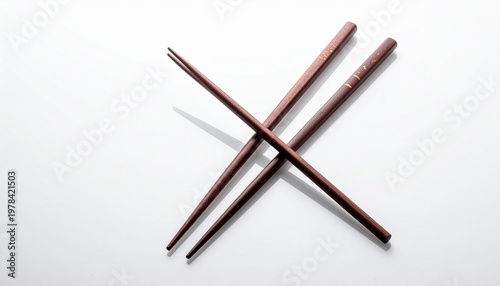 Overhead shot of crossed brown wooden chopsticks on white surface.