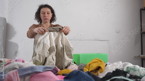 Woman searching through overflowing pile of clothes highlighting fast fashion and overconsumption
