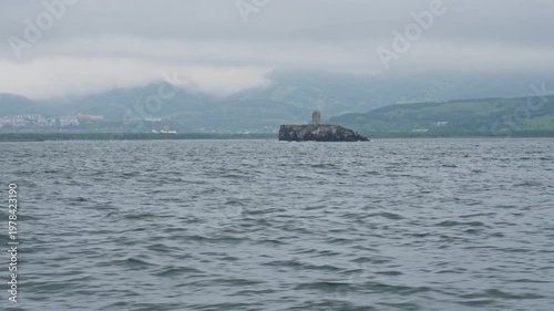A lighthouse against a backdrop of gloomy skies and stormy weather on a cliff in Avacha Bay in the Pacific Ocean of the Kamchatka Peninsula