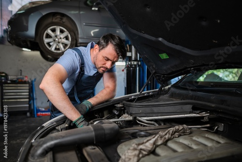 Schilderij op canvas Mechanic repairing car engine in auto repair shop