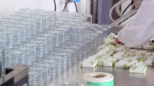 Factory worker checks butter packs on stainless table near empty jars. Factory worker sorts wrapped blocks scanning labels before packing cartons