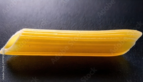 Close-up of a single piece of penne pasta on black.