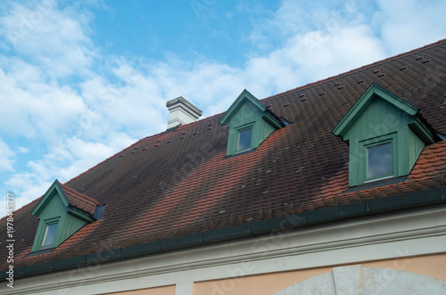 Beaver tail terracotta tiles roof with small green wooden dormer windows on traditional house, Hungary