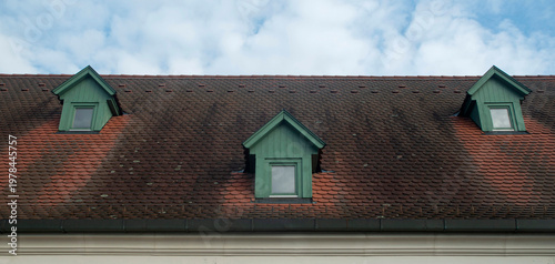 Beaver tail terracotta tiles roof with small green wooden dormer windows on traditional house, Hungary