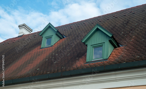 Beaver tail terracotta tiles roof with small green wooden dormer windows on traditional house, Hungary