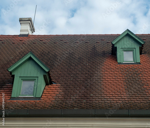 Beaver tail terracotta tiles roof with small green wooden dormer windows on traditional house, Hungary