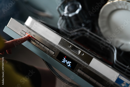 Woman finger pressing Eco button on dishwasher panel.