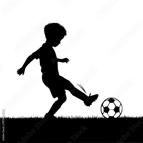 Silhouette of a boy kicking a soccer ball on a grassy field