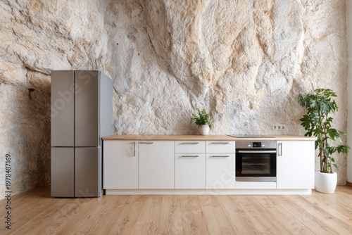 Modern kitchen cabinetry and refrigerator set against a natural rock wall.