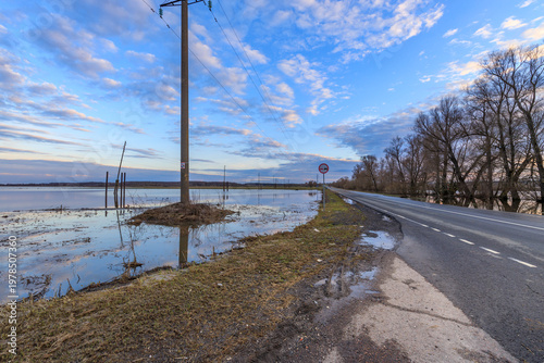 Принти на полотні Waterlogged road runs parallel to a calm body of water