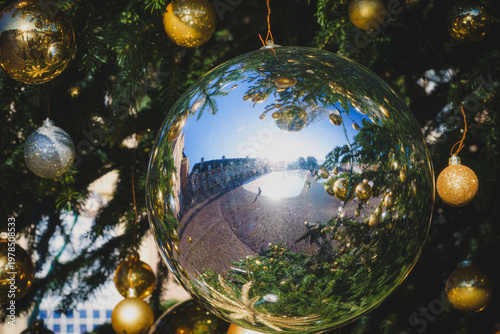 Sunlight glints off mirrored ornaments, reflecting a festive scene.