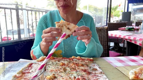 Happy Woman Eats a Slice of Fresh Pizza for Lunch in a Casual Outdoor Cafe