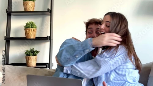 Excited Couple Reacts with Joy and Hugs to Good News on Laptop at Home
