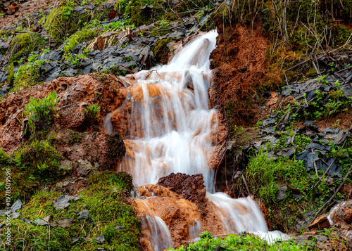 Photos photo of a noisy spring with a large amount of water, which precipitates iron spring lime