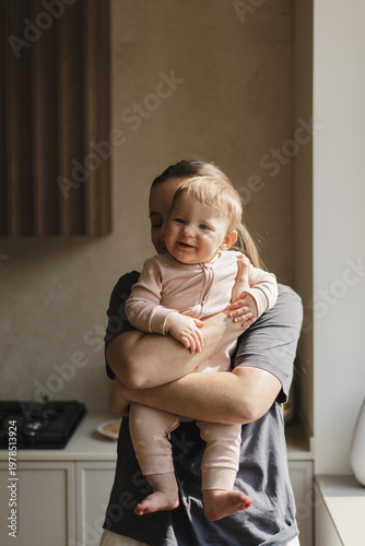 A mother is playing with her child. The sun is shining through a window, creating a warm atmosphere. Concept of baby care, early development, and healthy childhood life. Mother's Day