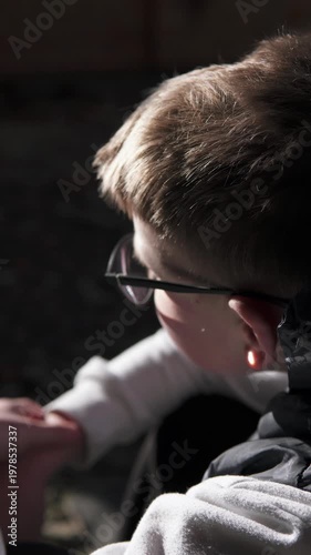 A lonely teenage boy sits in an abandoned brick building after school, away from people. The sunlight highlights his face as he reflects in solitude. The scene conveys themes of bullying, isolation.