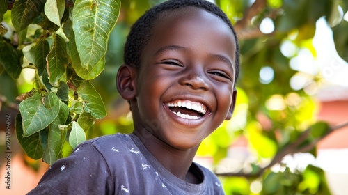Joyful African Boy Laughing in Sunlight Surrounded by Green Leaves and Nature's Beauty