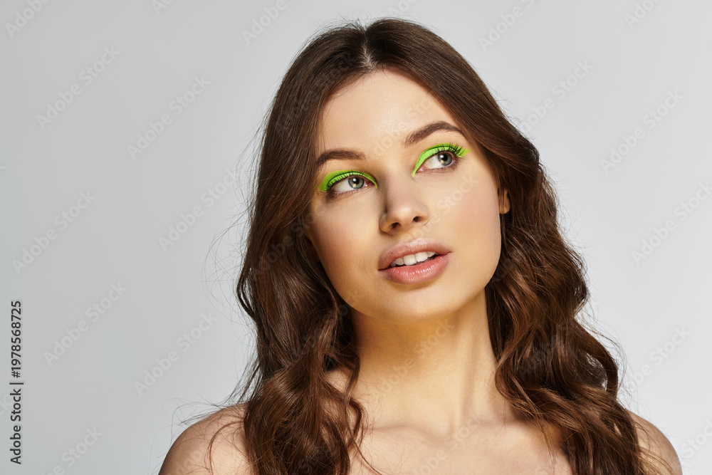 Fototapeta premium Bold makeup showcase featuring a young woman with vibrant green eyeshadow in a studio