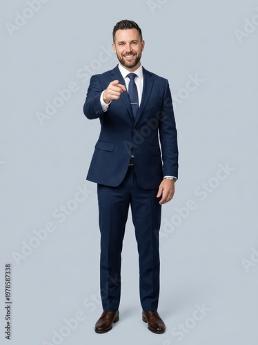 Smiling man in suit pointing toward the viewer