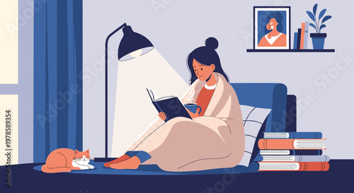 Young woman enjoys reading a book under a warm lamp while wrapped in a blanket on her couch with a sleeping cat.