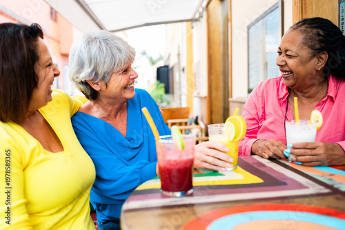 Multiracial senior friends having fun outside bar restaurant while drinking healthy smoothies - ugc content