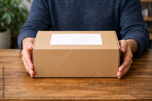 White labeled parcel on rustic table, close up of person holding box for home delivery