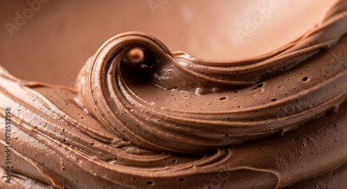 Rich smooth creamy chocolate frosting swirling in a tempting texture creating a decadent dessert topping for cakes and pastries with a warm brown hue and delicate air bubbles demonstrating