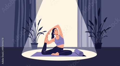 Dedicated woman practices a challenging yoga pose on a mat under a bright spotlight in a quiet, dark room at night.