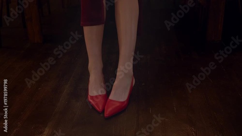 Slender legs dressed in red shoes.
