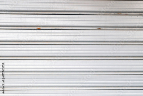 Detailed view of grey metallic security rolling shutters with parallel lines.