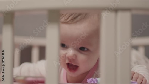 Happy baby girl resting in a crib at home playing and smiling