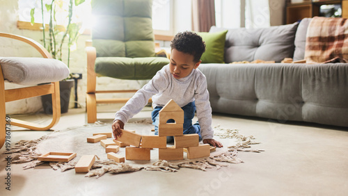 Φωτογραφία Child building wooden block house on floor in cozy living room environment