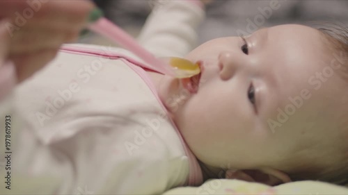 Mother giving medicine with a spoon to a crying baby girl