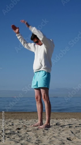 Man training on beach at sunrise, powerful workout, outdoor fitness routine.