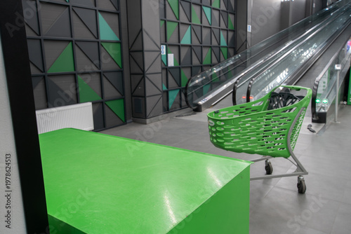 Shopping cart in a modern store near a moving escalator during daytime
