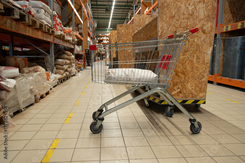 Shopping cart in a retail store aisle with goods on shelves during the day