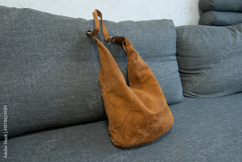 Soft brown bag placed on gray sofa in a modern living room during daytime