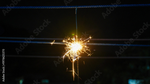 Sparkler firework glowing in the dark with bright sparks and light trails, captured in low light conditions, creating a dramatic and festive atmosphere.