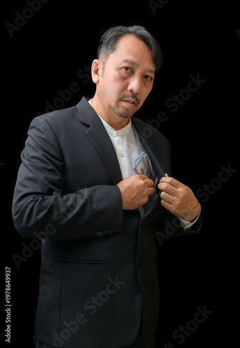 Businessman Hiding Money in Suit Pocket on Black Background