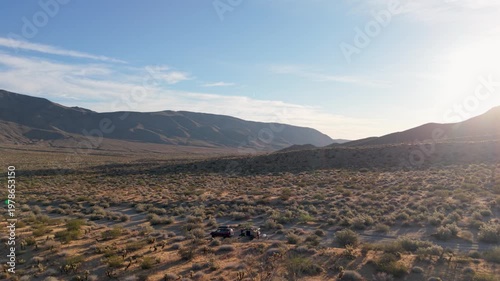 Teardrop camper sits in the Anza Borego Desert watching the desert landscape as the sun sets in Plum Canyon in California.