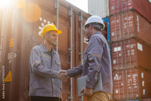Workers shaking hands at shipping container yard